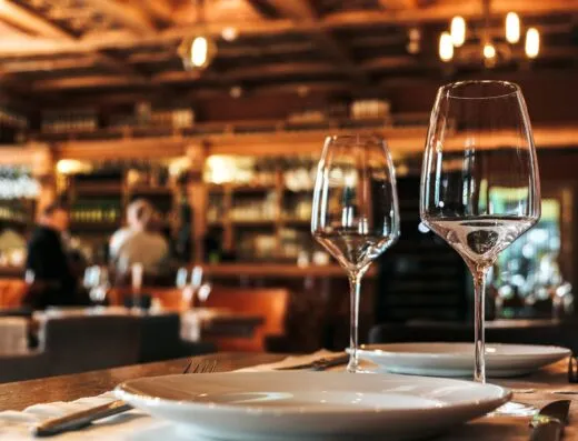 Mesa de comedor elegantemente decorada con cristalería en un ambiente acogedor y cálido de restaurante.