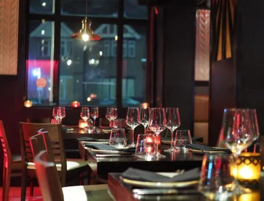 Un interior de restaurante sofisticado con una elegante mesa y luz de velas ambiente, creando una atmósfera acogedora.
