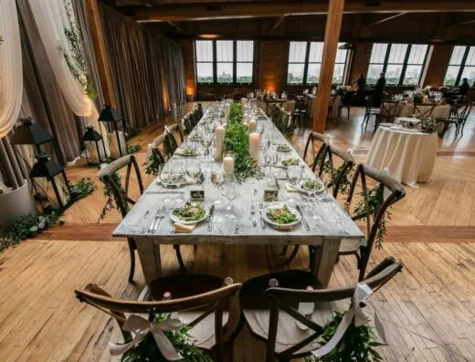 Configuración de mesa elegante para una recepción de boda en un loft de Chicago con velas y vegetación.