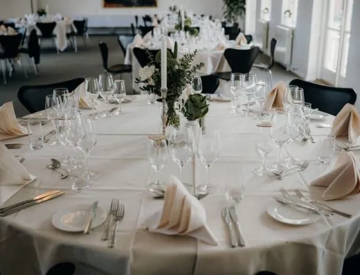 Una hermosa disposición de mesa para una recepción de bodas con vajilla elegante y un centro de mesa floral.
