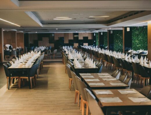 Amplio interior de restaurante de hotel con disposiciones de mesa formales organizadas neatamente, listas para un gran evento.