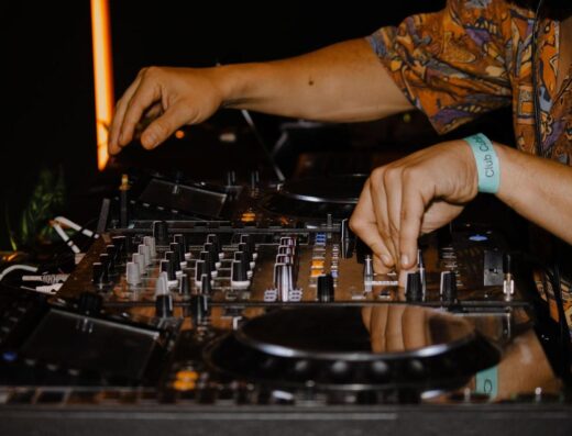 Primer plano de las manos del DJ mezclando música en un evento vibrante en un club nocturno.