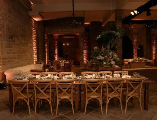 Espacio para eventos interior bellamente decorado con mesas de madera, sillas y arreglos florales.