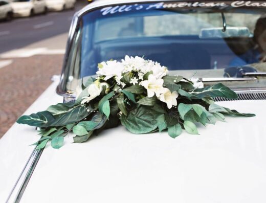 Un hermoso ramo floral decora un coche vintage, simbolizando amor y elegancia en una boda.