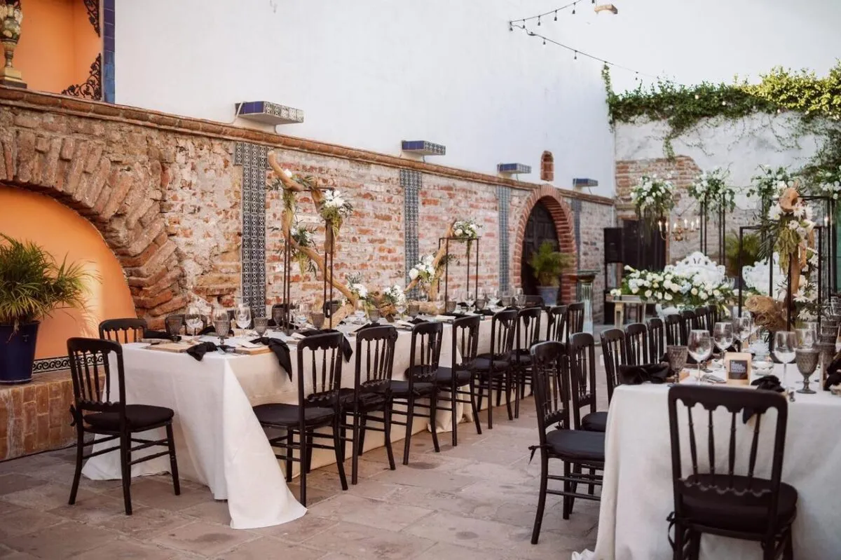 Elegante espacio de boda al aire libre con mesas, sillas y arreglos florales decorados (imagen de referencia)