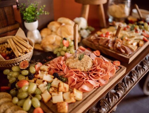 Deliciosa tabla de charcutería con carnes, quesos y frutas frescas en un montaje de evento.