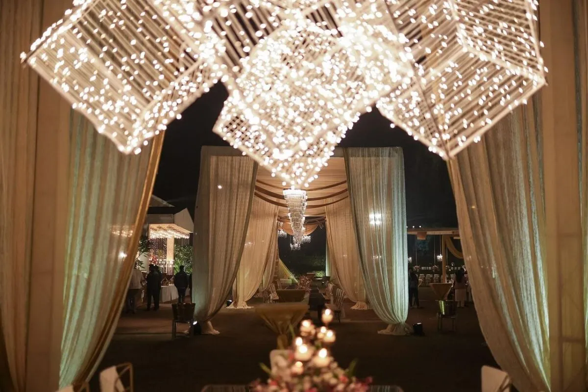 Un espacio de evento al aire libre bellamente iluminado, adornado con luces de hadas y cortinas drapeadas, creando una atmósfera mágica para la noche (imagen de referencia)