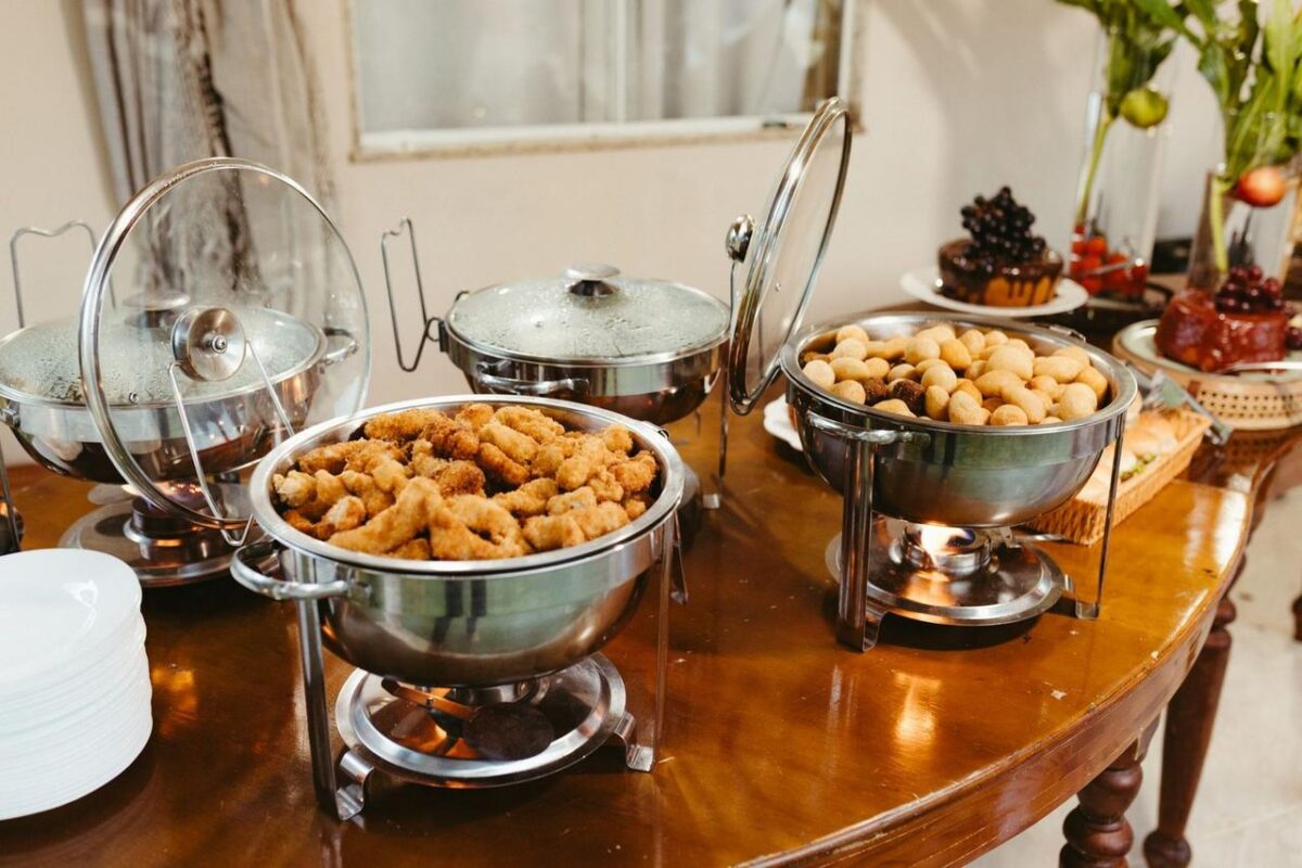 Delicioso buffet con variedad de aperitivos servidos en platos para calentar sobre una mesa de madera (imagen de referencia)