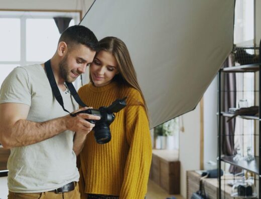 Una pareja feliz revisa fotos en una cámara réflex digital en un acogedor estudio interior.