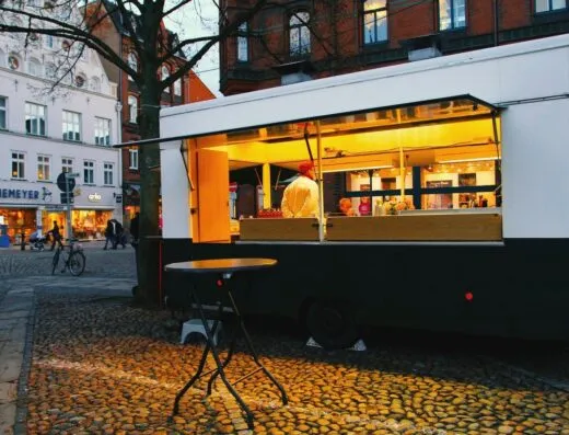 Vendedor de comida callejera en furgón iluminado por la noche en la plaza de la ciudad.