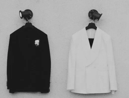 Par de chaquetas de traje en blanco y negro contrastantes colgadas en la pared, perfectas para ocasiones formales.