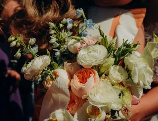 Primer plano de un ramo de novia con elegantes flores en un entorno soleado.