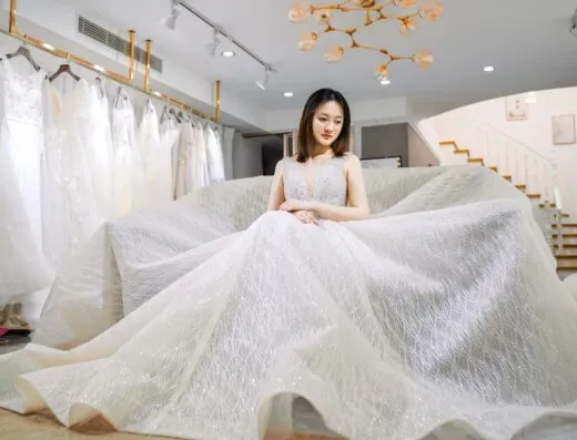 Una hermosa novia con un elegante vestido de novia dentro de una moderna boutique nupcial, contemplando su día especial.