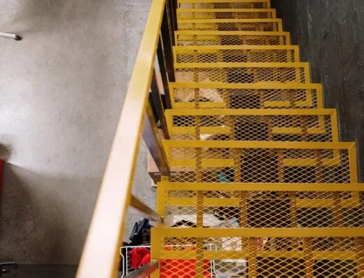 Escalera de metal amarilla brillante agrega un toque audaz a este espacio de loft industrial.