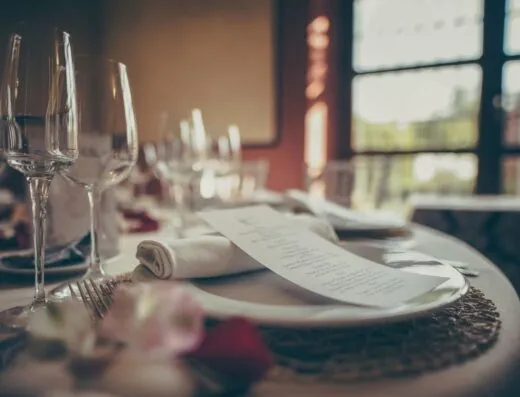 Un acogedor montaje de mesa para cenas elegantes en interiores, con vajilla elegante y un menú estiloso bajo una cálida iluminación.