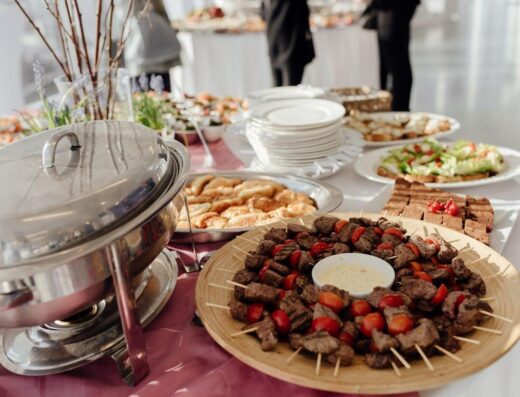 Elegante buffet con carnes en brochetas, ensaladas frescas y postres variados en un evento festivo.