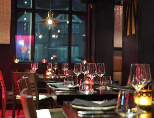 Un interior de restaurante sofisticado con una elegante mesa y luz de velas ambiente, creando una atmósfera acogedora.