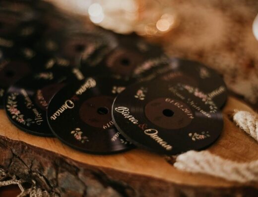 Acercamiento de posavasos personalizados para bodas con diseño floral romántico sobre una superficie de madera.