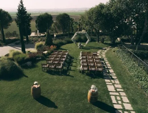 Un hermoso entorno de boda en jardín con sillas de madera y un arco floral en Torbalı, Turquía.