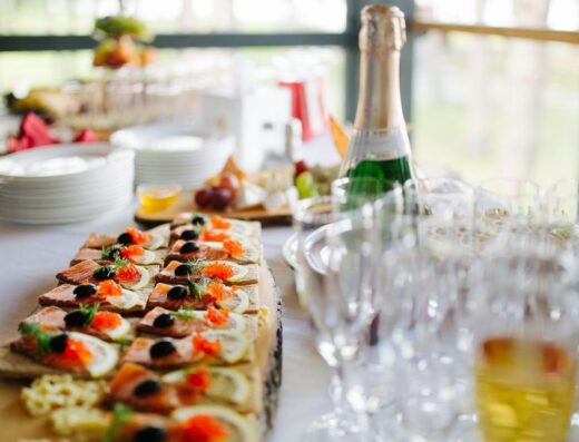 Plato de aperitivos gourmet servidos con champán para un evento elegante.