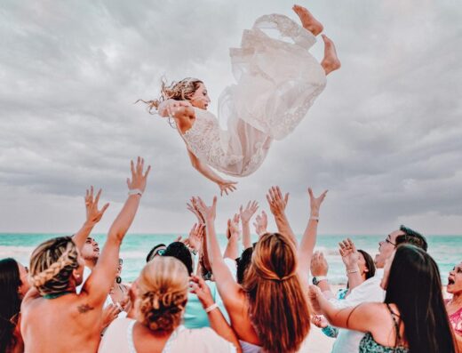 Novia alegre arrojada al aire durante una boda en la playa en Cancún, México.