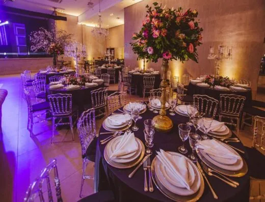 Decoración de comedor lujosa con arreglos florales, elegantes mesas y iluminación ambiental para un evento privado.