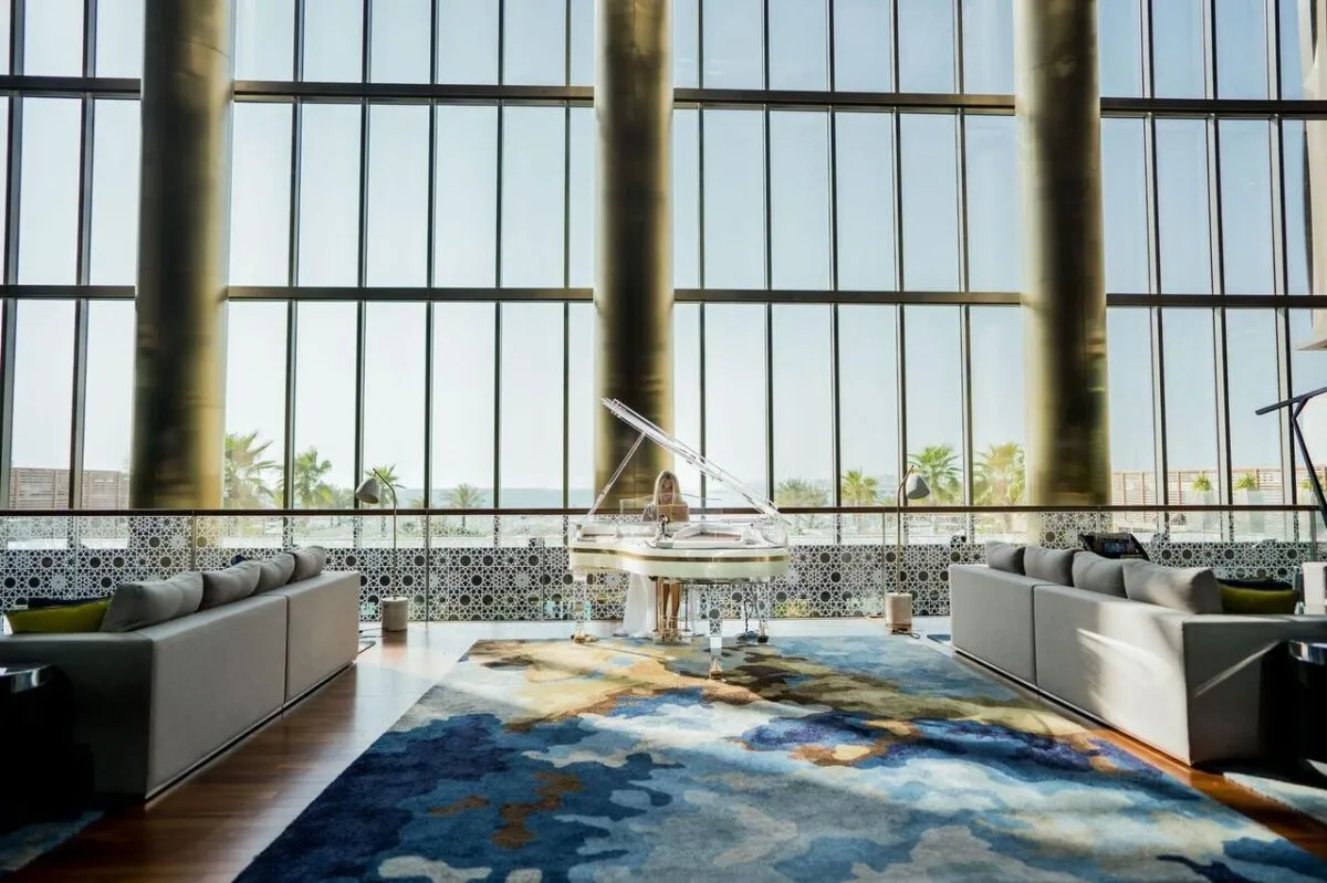 Un vestíbulo de hotel moderno en Dubái con un piano de cola, sofás mullidos y grandes ventanas que ofrecen una vista impresionante (imagen de referencia)