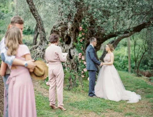 Ceremonia de boda romántica al aire libre con la novia y el novio bajo un árbol en flor.