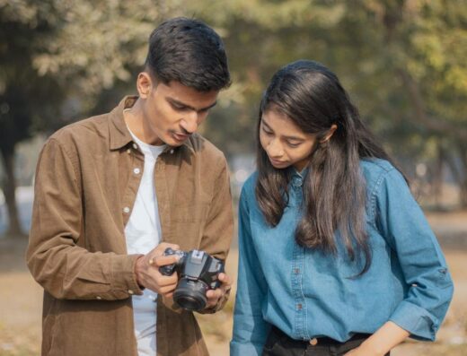 Dos jóvenes revisando fotos de la cámara al aire libre, disfrutando de la fotografía creativa.
