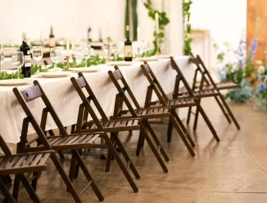 Mesa de banquete bellamente decorada con acentos florales y sillas de madera.