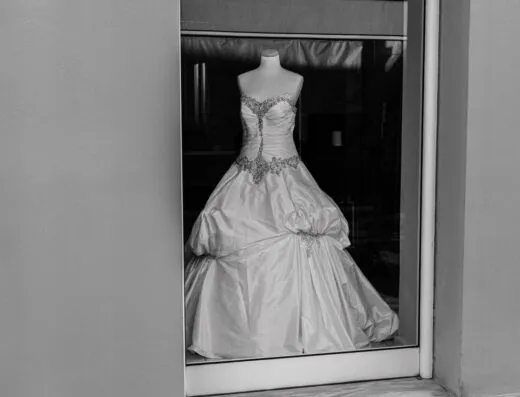 Una elegante toma en monocromo de un vestido de novia en un mannequin en la ventana de una boutique.