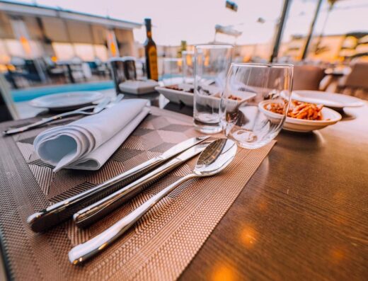 Primer plano de una elegante mesa puesta en un elegante restaurante al aire libre con iluminación ambiental.