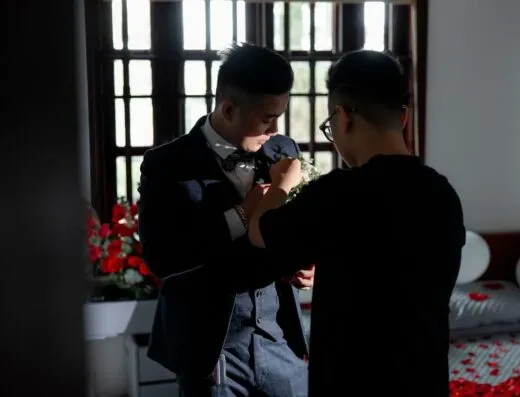 Novio en traje elegante ajustando el ojal antes de la ceremonia de boda, en un ambiente interior.