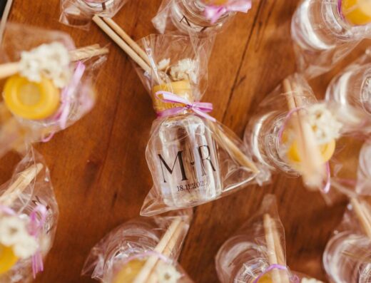 Exhibición estética de botellas de regalos de boda envueltas en papel transparente con palitos aromáticos.