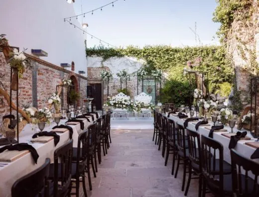 Mesa de boda al aire libre bellamente decorada con arreglos florales y encanto rústico.
