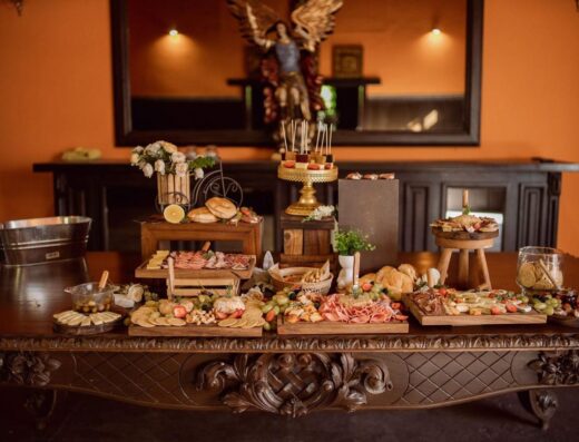 Una mesa de buffet bellamente dispuesta con una variedad de quesos, embutidos y una decoración elegante.