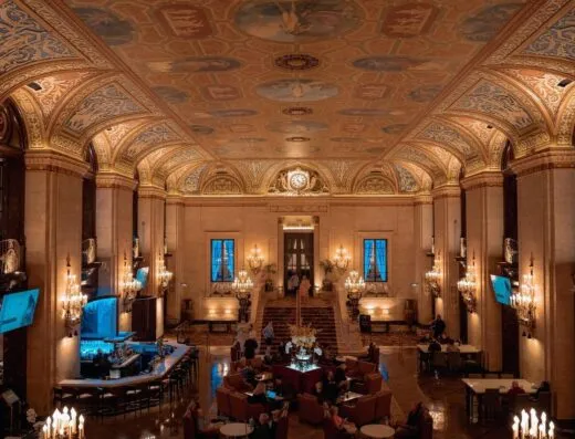 Lobby de hotel lujoso con techo ornamentado y elegantes candelabros.