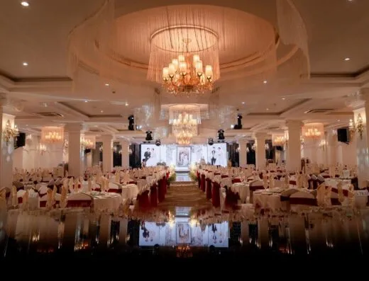 Salón lujoso bellamente organizado para un gran evento nocturno, con candelabros iluminando la decoración.