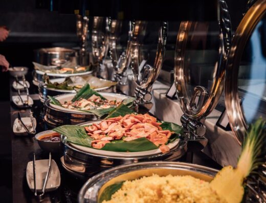 Montaje de buffet elegante con platos tropicales sobre hojas de plátano, ideal para inspiración en catering de eventos.