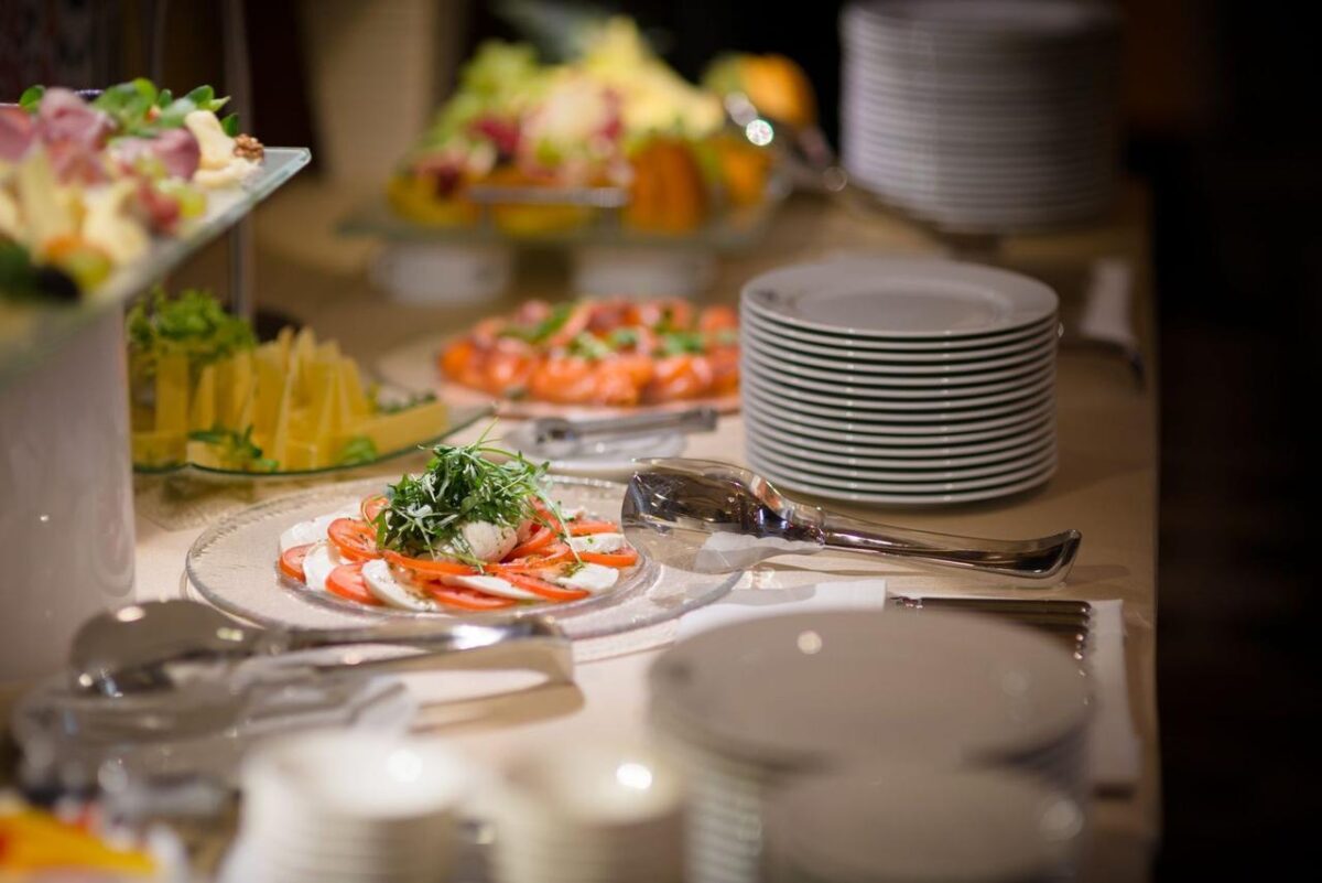 Un buffet bellamente decorado con ensalada Caprese y frutas frescas sobre un mantel blanco (imagen de referencia)