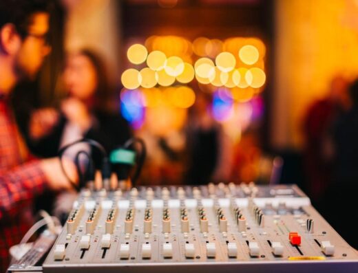 Primer plano del mezclador de audio con fondo borroso en un evento interno animado.