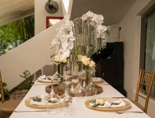 Elegante arreglo de mesa con flores blancas en jarrones altos, perfecto para bodas o cenas elegantes.