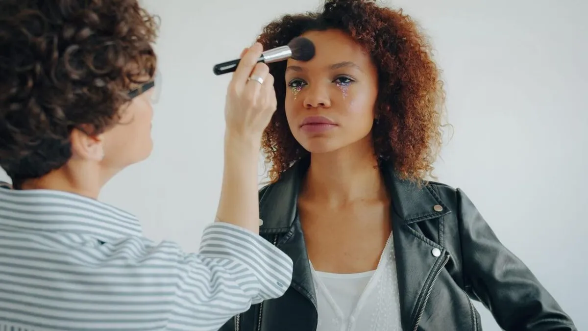 Maquilladora profesional aplicando maquillaje a una joven en el interior de un edificio (imagen de referencia)