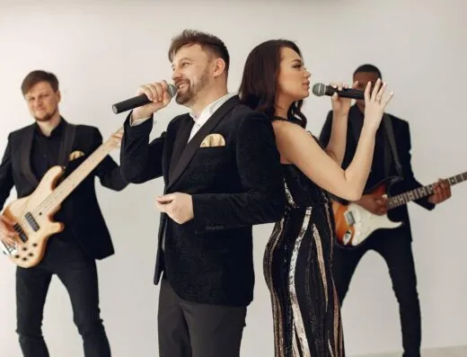 Una banda elegante actuando en el escenario con cantantes y músicos capturados en poses dinámicas.