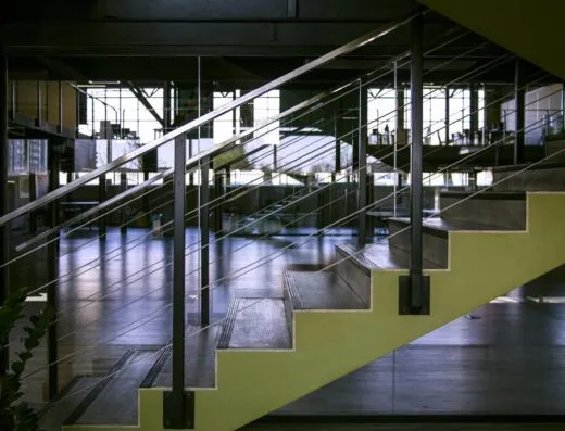 Interior espacioso con escaleras modernas, barandillas de vidrio y elementos de diseño metálico.