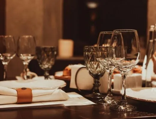 Arreglo de mesa de cena sofisticado con cristalería y luz de velas para una experiencia gastronómica de lujo.