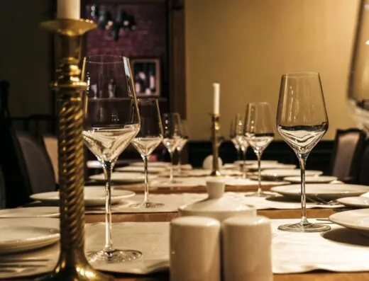 Configuración de mesa lujosa con copas de vino y candelabros en un elegante comedor.