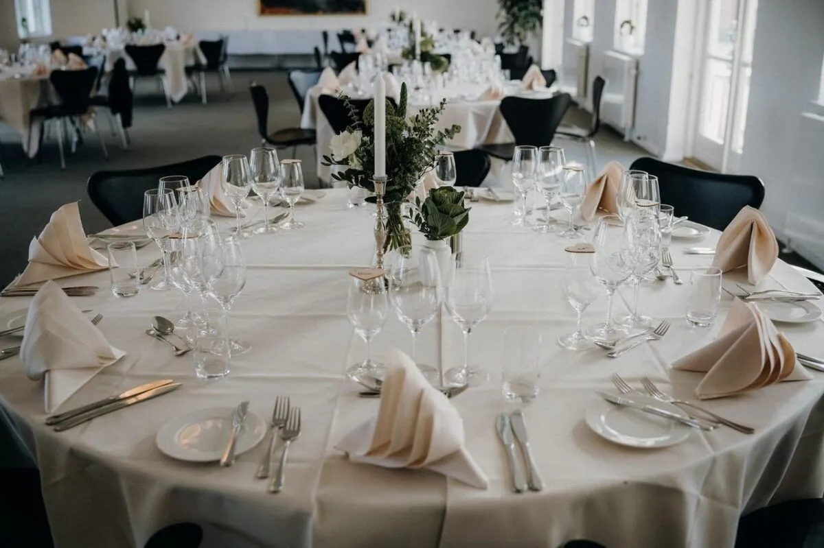 Una hermosa disposición de mesa para una recepción de bodas con vajilla elegante y un centro de mesa floral (imagen de referencia)