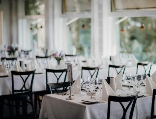 Mesas de comedor bellamente decoradas, perfectas para una recepción de boda o evento formal de cena, capturadas en el interior.