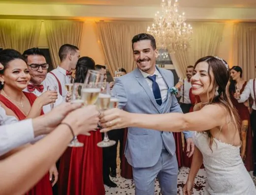 Una novia y un novio alegres brindan con los invitados en una animada celebración de boda en interiores.